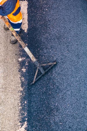 Téléchargez les photos : Travailleur sur asphalte machine de pavage pendant les travaux de réparation de la rue de la route. Concentration sélective - en image libre de droit