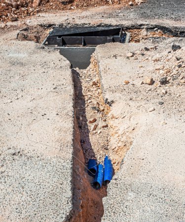 Téléchargez les photos : Excavation routière sur un chantier de construction de conduits pour la pose de câbles à fibres optiques et électriques - en image libre de droit