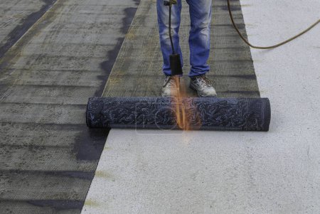 Téléchargez les photos : Travailleurs isolant toit avec membrane de bitume. Détails d'imperméabilisation sur le chantier de construction. Détails du système et installation sur le toit plat. - en image libre de droit