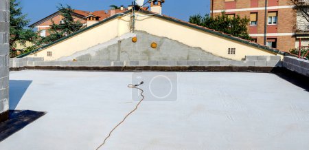 Téléchargez les photos : Terrasse plate d'une maison prête pour le pavage à membrane bitumineuse. Torche au gaz propane est prêt sur la terrasse pour l'application de la membrane bitumineuse - en image libre de droit
