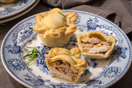 Tasty homemade baked chicken pies decorated with rosemary on plate