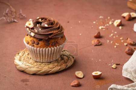 Téléchargez les photos : Muffins aux pépites de chocolat décorés de ganache au chocolat et noisette sur un comptoir de cuisine. - en image libre de droit