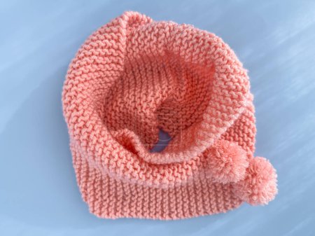 Weiche rosa Spitze gestrickter runder Schal isoliert auf pastellblauem Hintergrund. Mode als Accessoire für Kinder