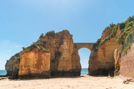 Detailed View of arched bridge with sailboat in Students Beach in Lagos, Algarve, Portugal