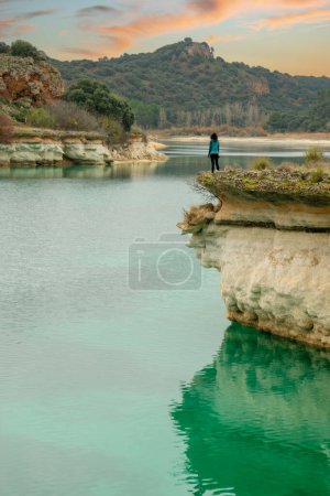 Photo for Person alone contemplating the lake from a cliff and enjoying nature in the lagoons of Ruidera, Spain. Traveling alone to relax. - Royalty Free Image