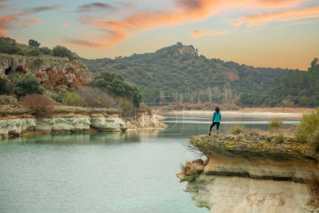 Photo for Person alone contemplating the lake from a cliff and enjoying nature in the lagoons of Ruidera, Spain. Traveling alone to relax. - Royalty Free Image