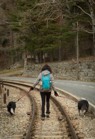 Mujer con dos perros paseando por las vías del tren en la estación Camorritos de Cercedilla, Madrid. España