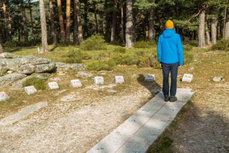 Young man hiker with stone sundial in the middle of the forest in Cercedilla, Madrid. Sierra de Guadarrama National Park, Spain