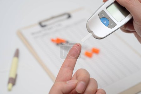 Foto de El hombre mide su azúcar en sangre. Glucosímetro, análisis de sangre, concepto de diabetes. - Imagen libre de derechos