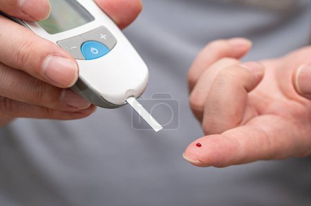 Foto de El hombre mide su azúcar en sangre. Glucosímetro, análisis de sangre, concepto de diabetes. - Imagen libre de derechos
