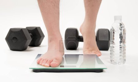 Téléchargez les photos : Asian middle-aged man's feet measuring weight - en image libre de droit