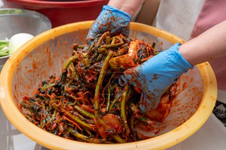 Téléchargez les photos : Le processus de fabrication d'un plat traditionnel coréen, le kimchi. Une femme portant des gants prépare divers ingrédients nécessaires pour le kimchi. - en image libre de droit