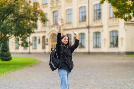 The girl with the backpack is walking to school, university, happy and waving after. High quality photo