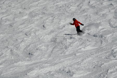 Téléchargez les photos : Snowboarder running down the slope leaving behind a snow powder. - en image libre de droit