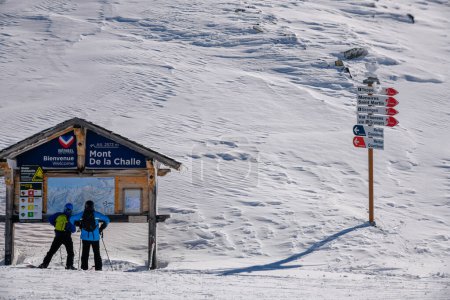 Téléchargez les photos : Deux skieurs explorent la carte de la zone Mont de la Challe de la station de ski Meribel en France. - en image libre de droit