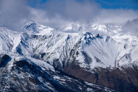 Téléchargez les photos : Paysage de montagne enneigé à couper le souffle au domaine skiable de Meribel en France. Journée ensoleillée d'hiver, ciel bleu, nuages et sommets. - en image libre de droit