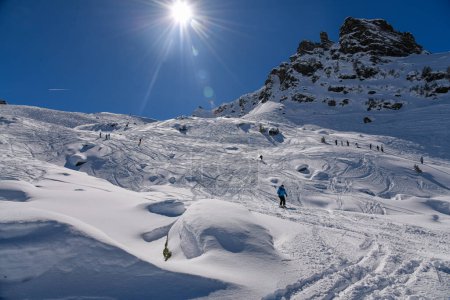 Téléchargez les photos : Journée ensoleillée d'hiver et bonnes conditions de neige à la station de ski Meribel en France. Les skieurs avancés explorent le terrain hors piste avec un paysage à couper le souffle autour. - en image libre de droit