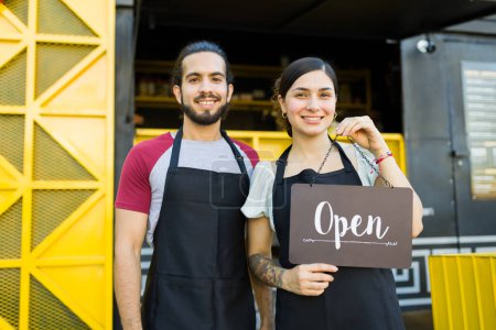 Téléchargez les photos : Joyeux vendeur de stalles et cuisinier souriant après l'ouverture du camion de restauration rapide - en image libre de droit