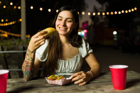 Foto de Alegre hermosa mujer sonriendo antes de tomar un bocado y comer tacos mexicanos del vendedor ambulante - Imagen libre de derechos