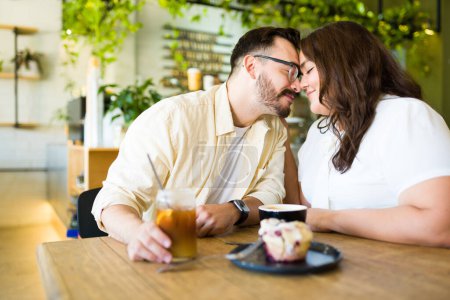 Foto de Romántica hermosa pareja tocándose la frente y relajándose durante una cita tomando café - Imagen libre de derechos
