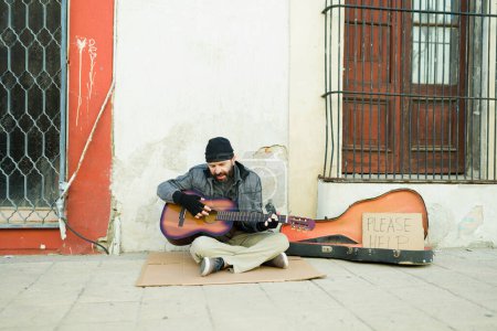 Téléchargez les photos : Pauvre mendiant sans abri chantant et jouant de la guitare tout en demandant de l'argent dans la rue - en image libre de droit