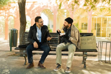 Téléchargez les photos : Genre homme caucasien assis sur un banc avec un sans-abri affamé mangeant une soupe chaude et demandant de l'aide - en image libre de droit
