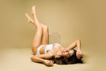 Relaxed cheerful young woman in underwear having fun and relaxing with her smooth beautiful legs up