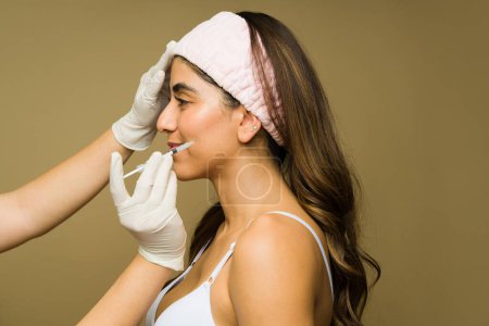 Téléchargez les photos : Belle jeune femme obtenant des injections de toxine botulinique sur son visage pour prévenir les rides lors d'une procédure de beauté cosmétique - en image libre de droit