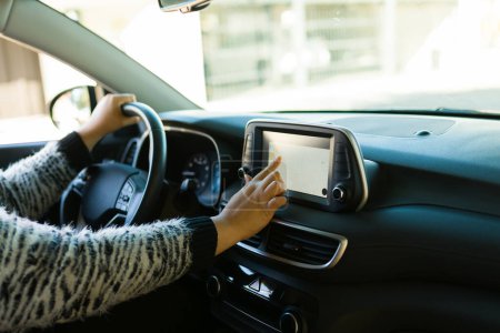 Téléchargez les photos : Gros plan d'une jeune femme utilisant le système de navigation GPS à écran tactile pour les directions pendant la conduite de la voiture - en image libre de droit