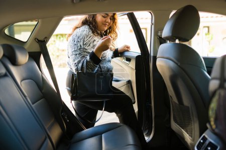 Téléchargez les photos : Surpoids jeune femme monter sur le siège passager tout en faisant un voyage sur une application de partage de ride - en image libre de droit