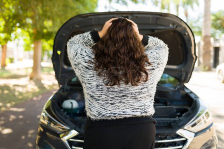 Foto de Mujer grande y ansiosa vista desde atrás sintiéndose estresada sosteniendo la cabeza debido a su coche roto - Imagen libre de derechos