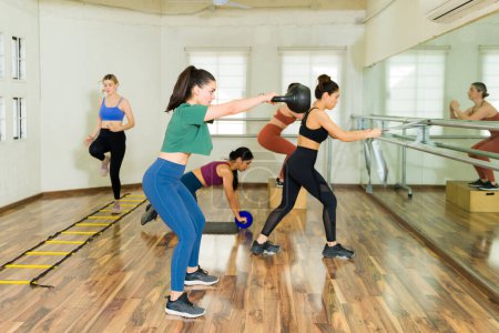 Foto de Grupo de mujeres haciendo ejercicio con pesas de kettlebell durante un entrenamiento de intervalos de alta intensidad en el gimnasio - Imagen libre de derechos