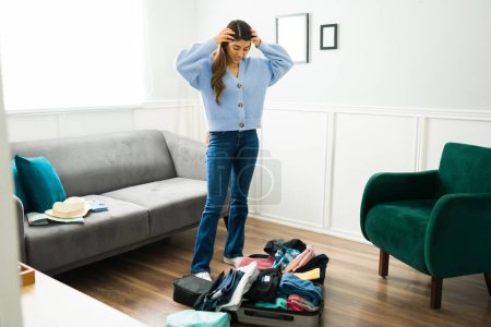 Foto de Mujer preocupada ansiosa que parece desorganizada mientras prepara su ropa y su maleta antes de irse de viaje sola. - Imagen libre de derechos