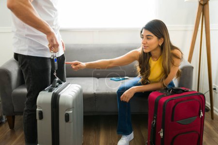 Foto de Pareja latina sonriente usando una balanza de equipaje para pesar sus maletas antes de irse de vacaciones juntos - Imagen libre de derechos