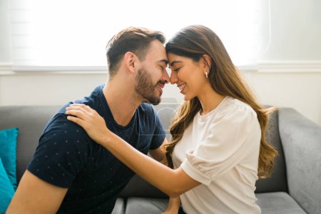 Téléchargez les photos : Couple romantique amoureux toucher leur front et partager un moment d'amour lors d'un rendez-vous à la maison - en image libre de droit