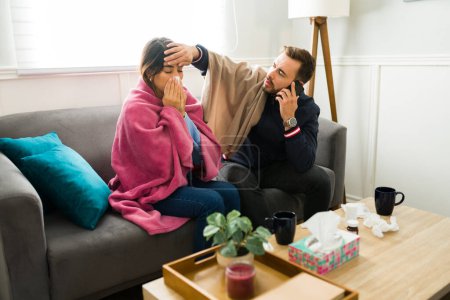 Téléchargez les photos : Homme malade inquiet vérifier sur sa petite amie pour la fièvre tout en regardant malade et appeler le médecin au téléphone - en image libre de droit