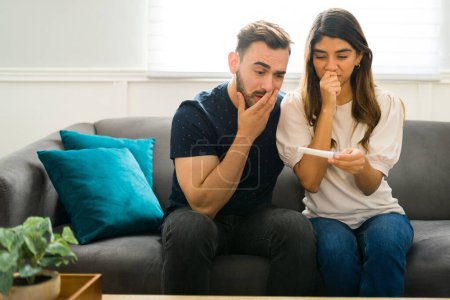 Téléchargez les photos : Couple inquiet regardant stressé tout en regardant un test de grossesse positif ou négatif ensemble - en image libre de droit