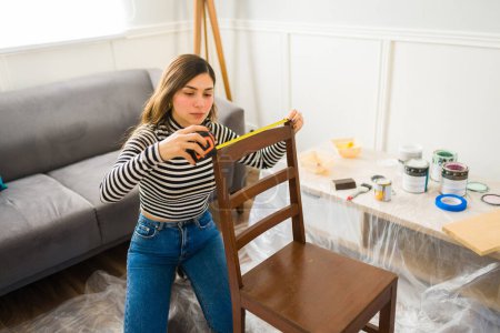 Téléchargez les photos : Femme latine mesurant une chaise tout en appréciant son hobby de retournement ou de restauration de meubles - en image libre de droit