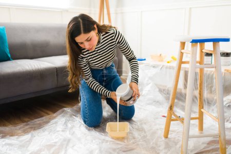 Téléchargez les photos : Femme hispanique préparant de la peinture pour démarrer son projet de rénovation de meubles à la maison - en image libre de droit