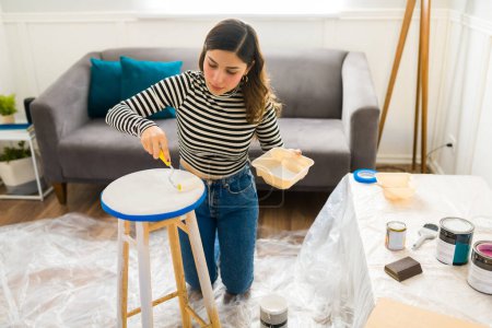 Téléchargez les photos : Belle femme peignant ses meubles et faisant un projet de restauration de la maison ou un passe-temps - en image libre de droit