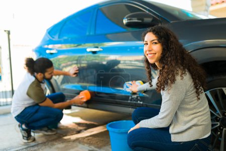 Téléchargez les photos : Magnifique femme heureuse laver la voiture avec son petit ami tout en faisant un contact visuel - en image libre de droit