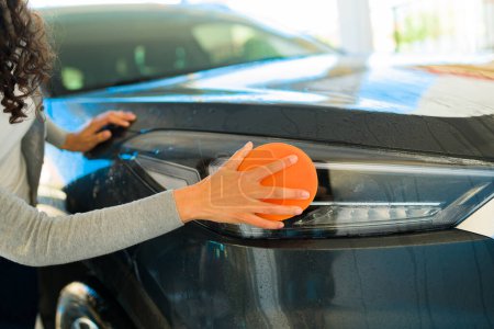 Téléchargez les photos : Gros plan des mains d'une jeune femme lavant la voiture avec une éponge - en image libre de droit