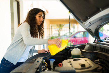 Foto de Mujer atractiva revisando el motor y cambiando el aceite de su coche en el garaje - Imagen libre de derechos