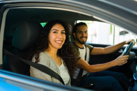 Foto de Hermosa mujer latina y hombre feliz conduciendo y viajando en el coche mientras sonríe - Imagen libre de derechos