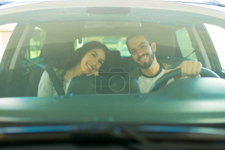 Foto de Atractiva pareja feliz sonriendo mientras conducen juntos en el coche buscando alegre - Imagen libre de derechos