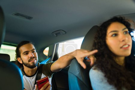 Téléchargez les photos : Passager latin donnant des directions au conducteur du service de covoiturage dans la voiture - en image libre de droit