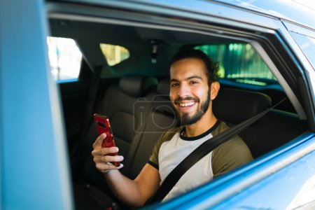 Téléchargez les photos : Portrait d'un homme séduisant regardant heureux tout en faisant un voyage dans la voiture d'un service de covoiturage - en image libre de droit