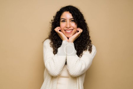 Photo for Adorable hispanic woman with her hands on the chin looking adorable and happy while smiling against a studio background - Royalty Free Image