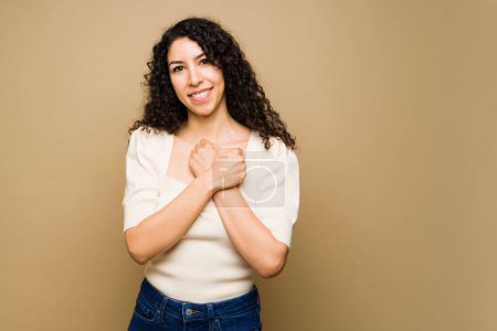 Photo for Cheerful young woman feeling in love putting her hands on her chest and using american sign language - Royalty Free Image