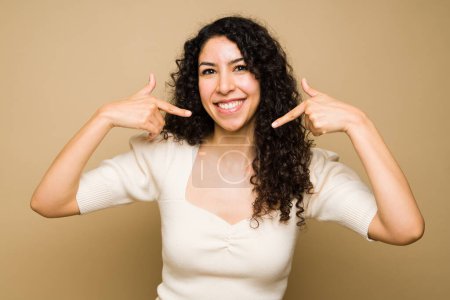 Foto de Excited attractive woman with a big smile pointing to her white teeth and smiling looking happy - Imagen libre de derechos